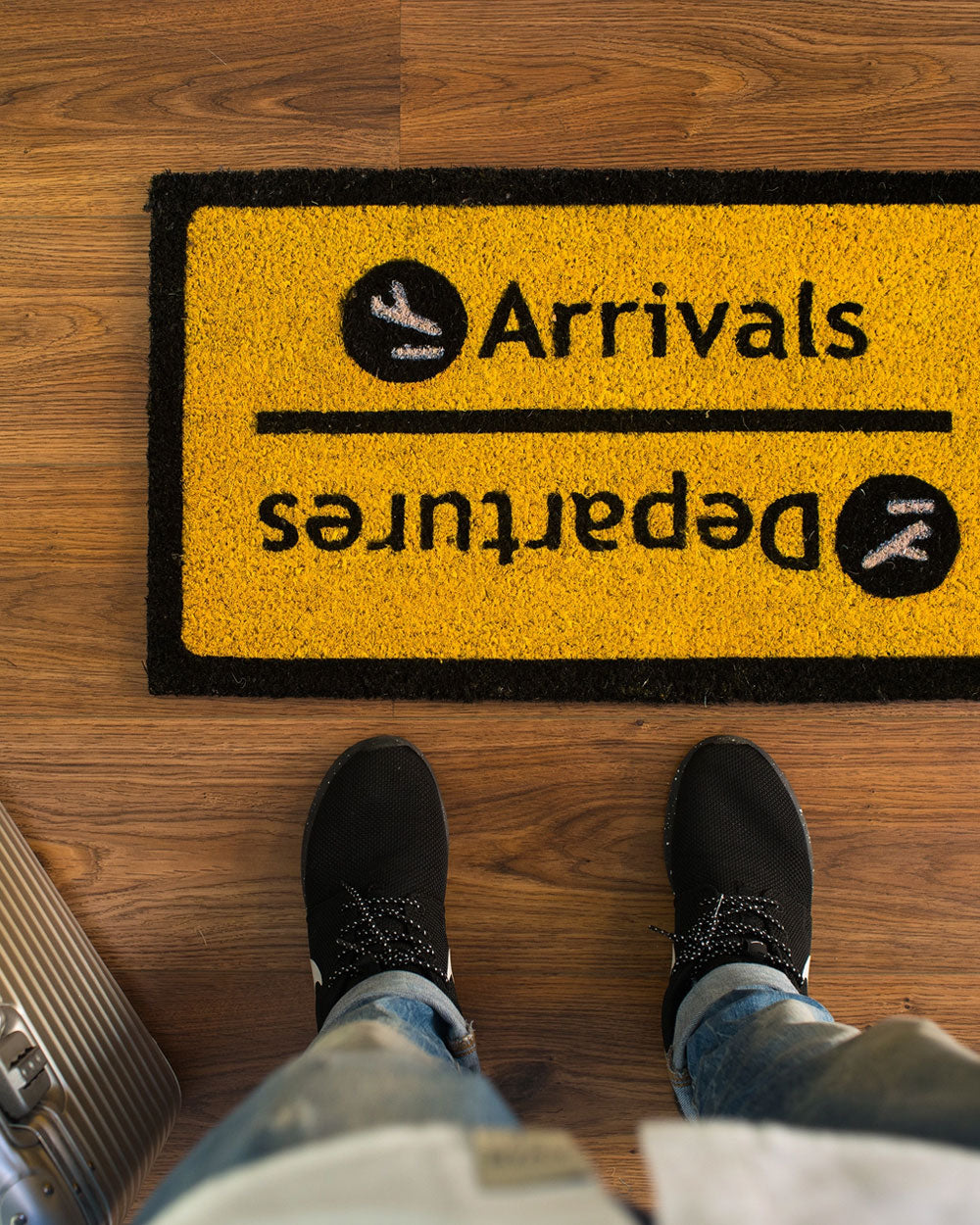 Yellow doormat with black border, Arrivals text and direction arrows.