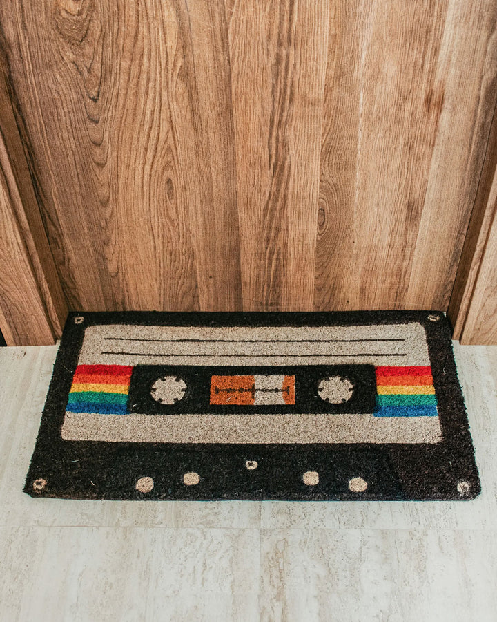 Cassette tape doormat with black border, colorful cassette graphic, and corner grommets