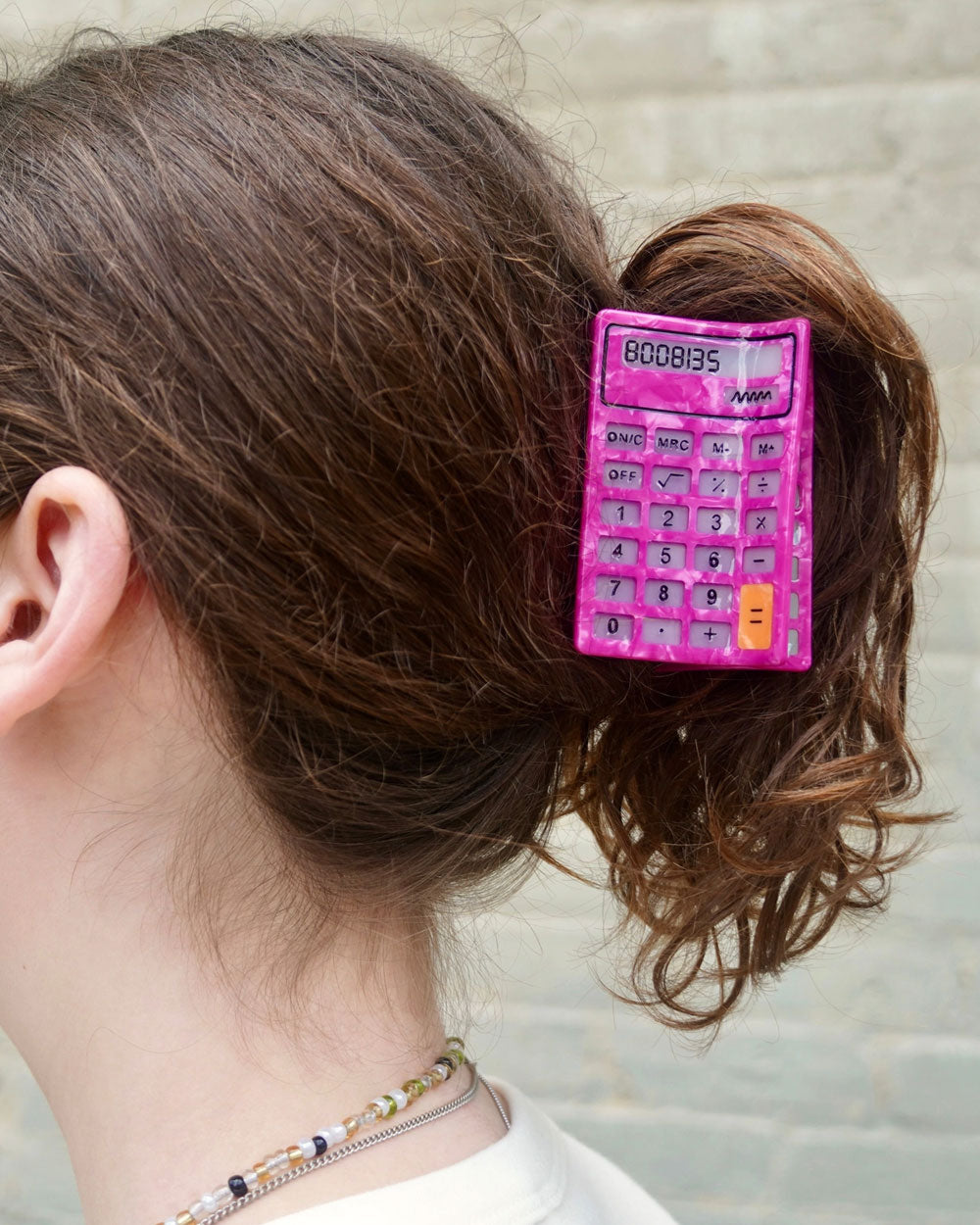 Pink calculator hair claw clip clipped to curly brown hair