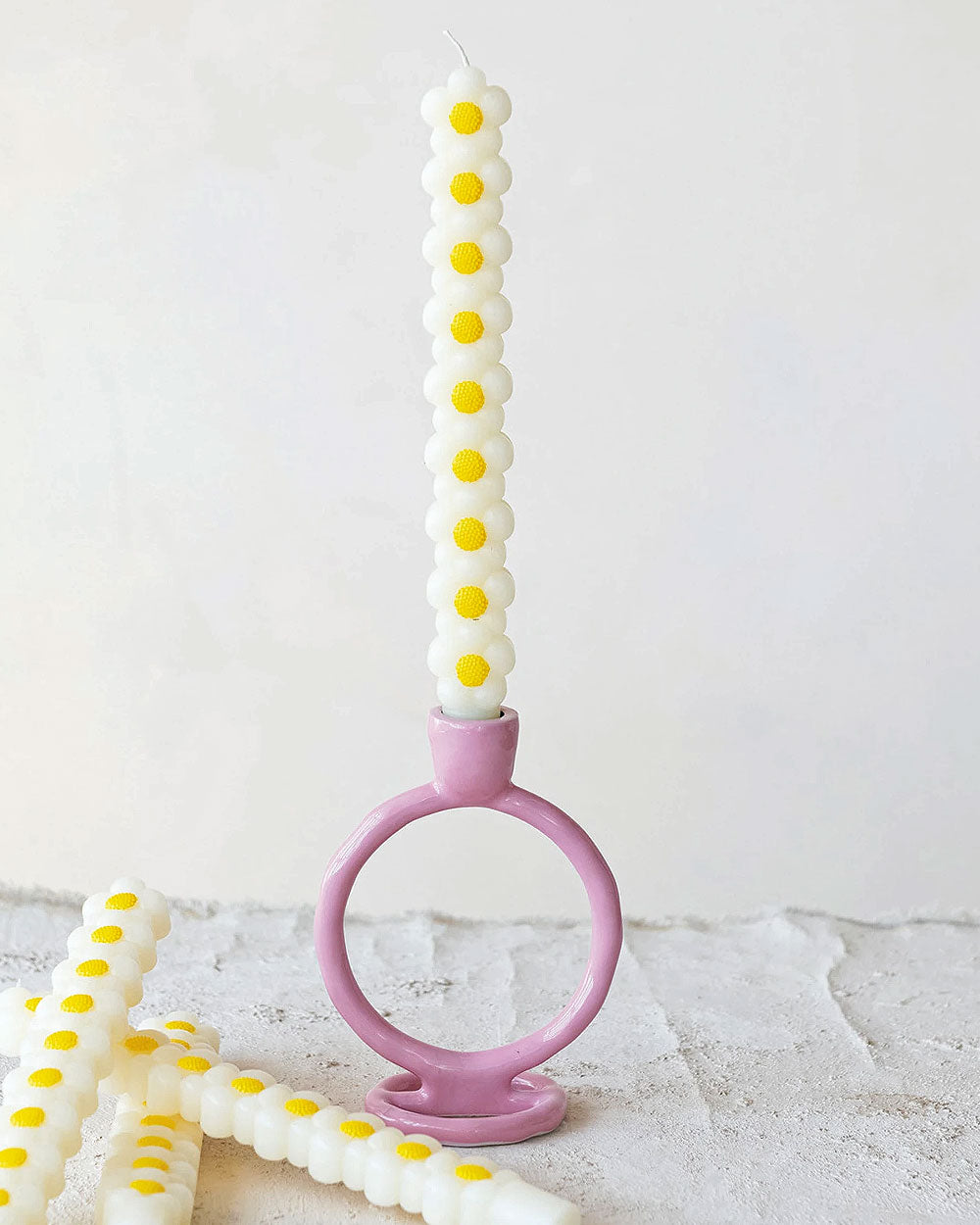 White daisy taper candle with yellow blooms and pink circular base