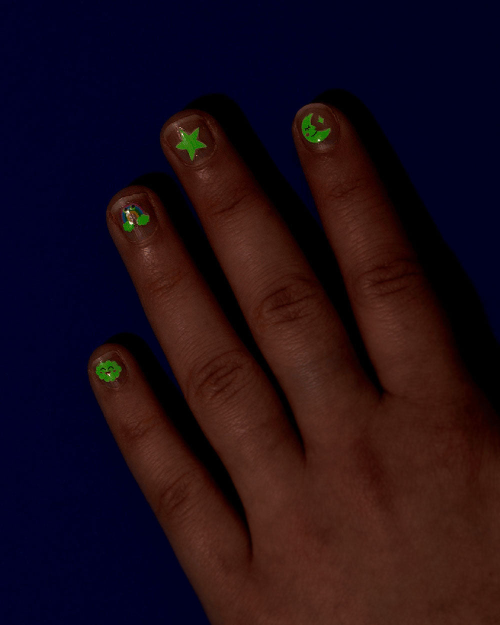 Fingertips with small green glow nail stickers featuring stars and character faces