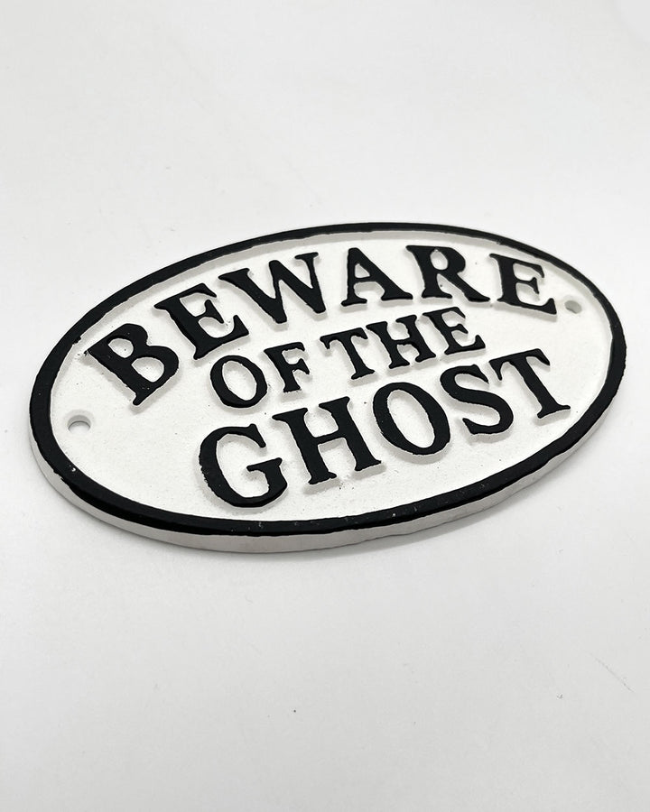 Oval decorative sign: white face, black border, “BEWARE OF THE GHOST” text
