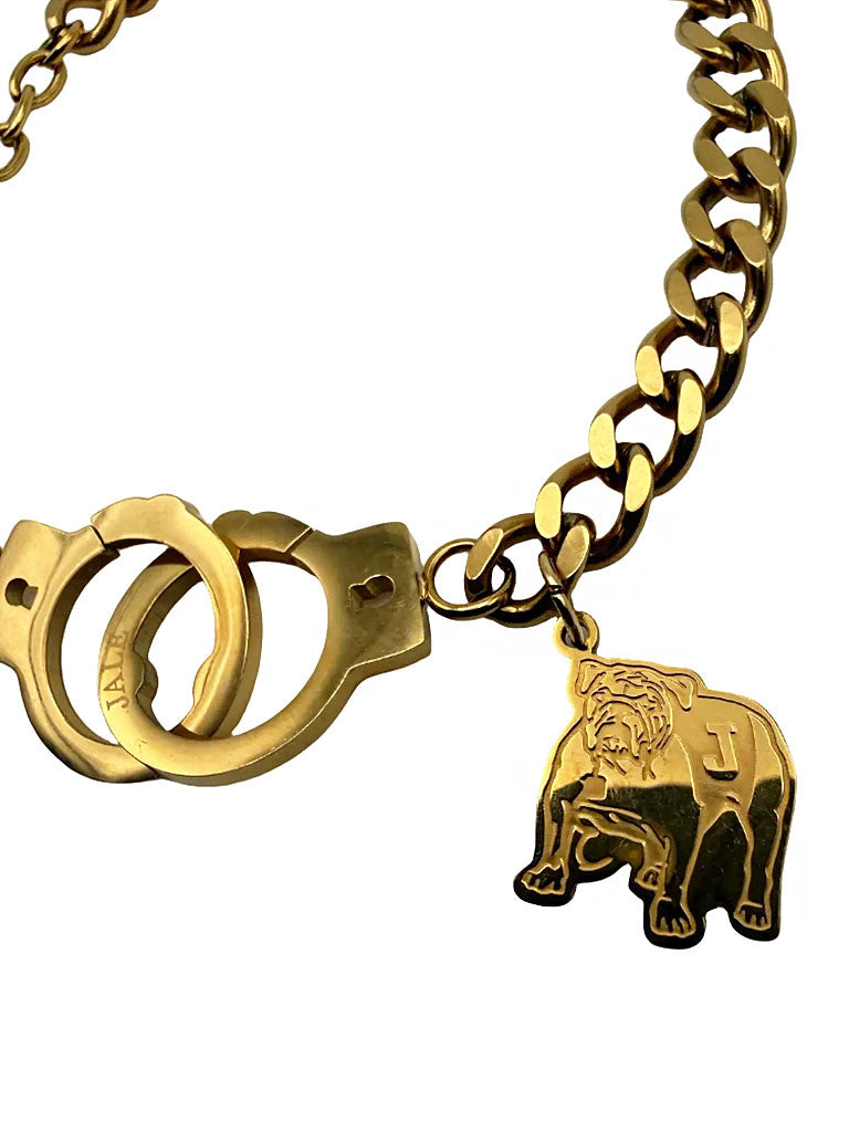 Gold chain bracelet close-up with handcuff centerpiece and animal mascot charm