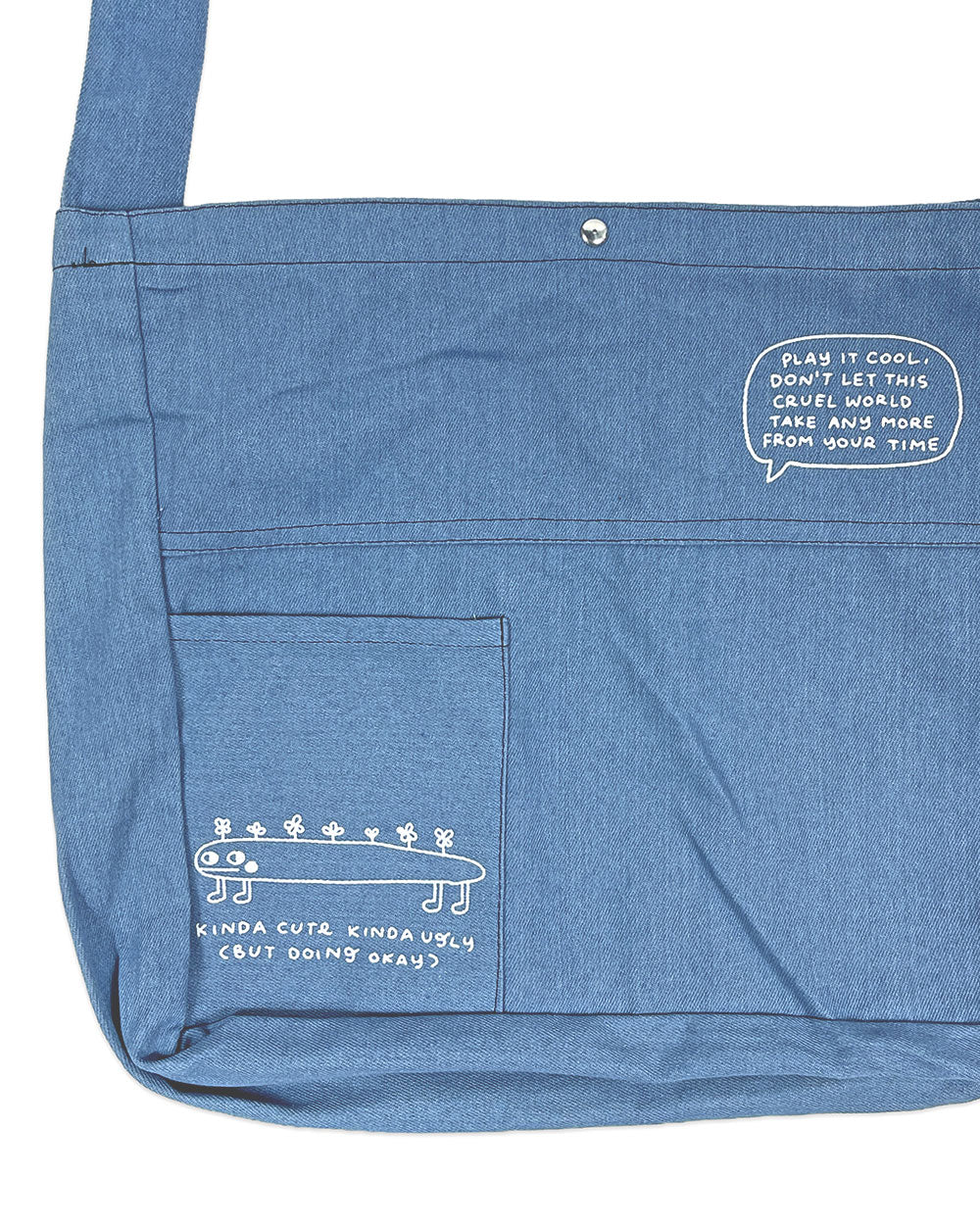 Blue denim tote bag with front panel pocket and stitched graphic detail
