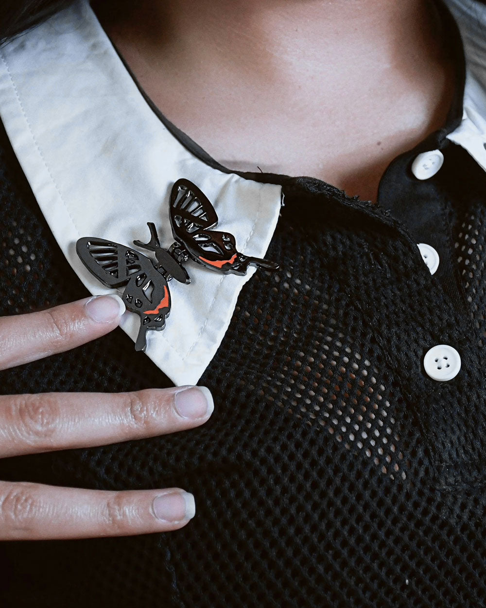Winged butterfly pins on shirt collar, black/silver metal with red accents