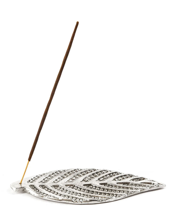 Metal leaf incense burner with incense stick resting on embossed center