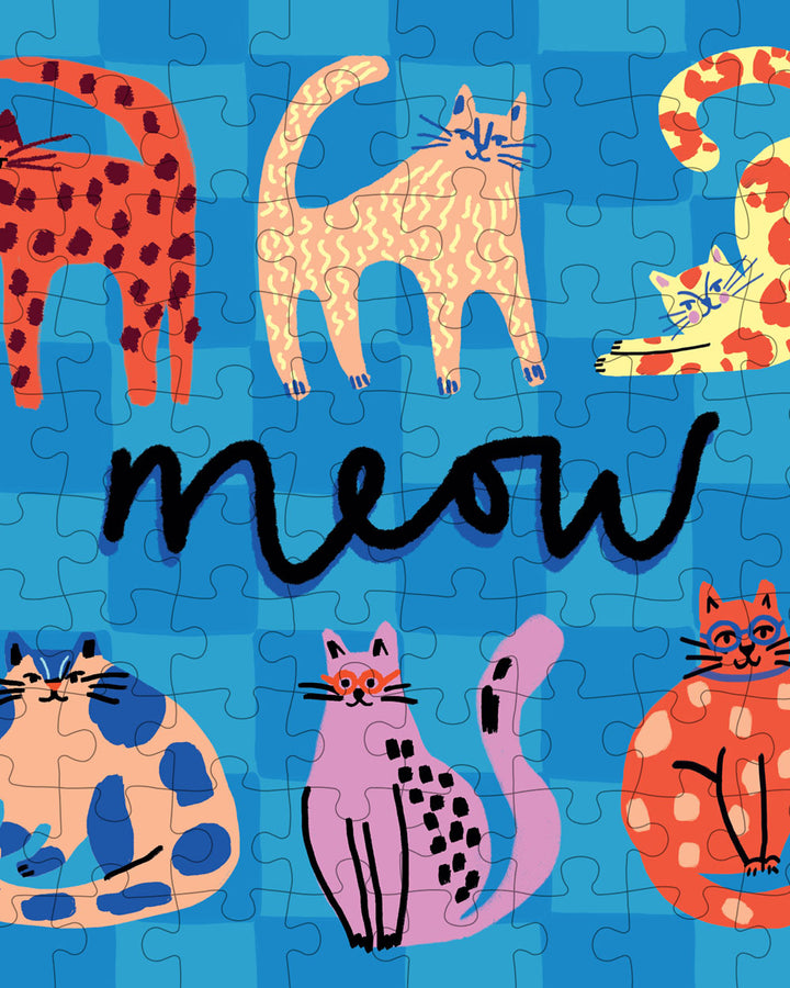 Mini jigsaw puzzle close-up with cats, 'meow' script, and interlocking pieces