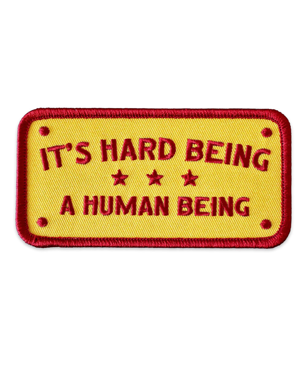 Yellow embroidered patch with red border and text reading “It’s Hard Being a Human Being”