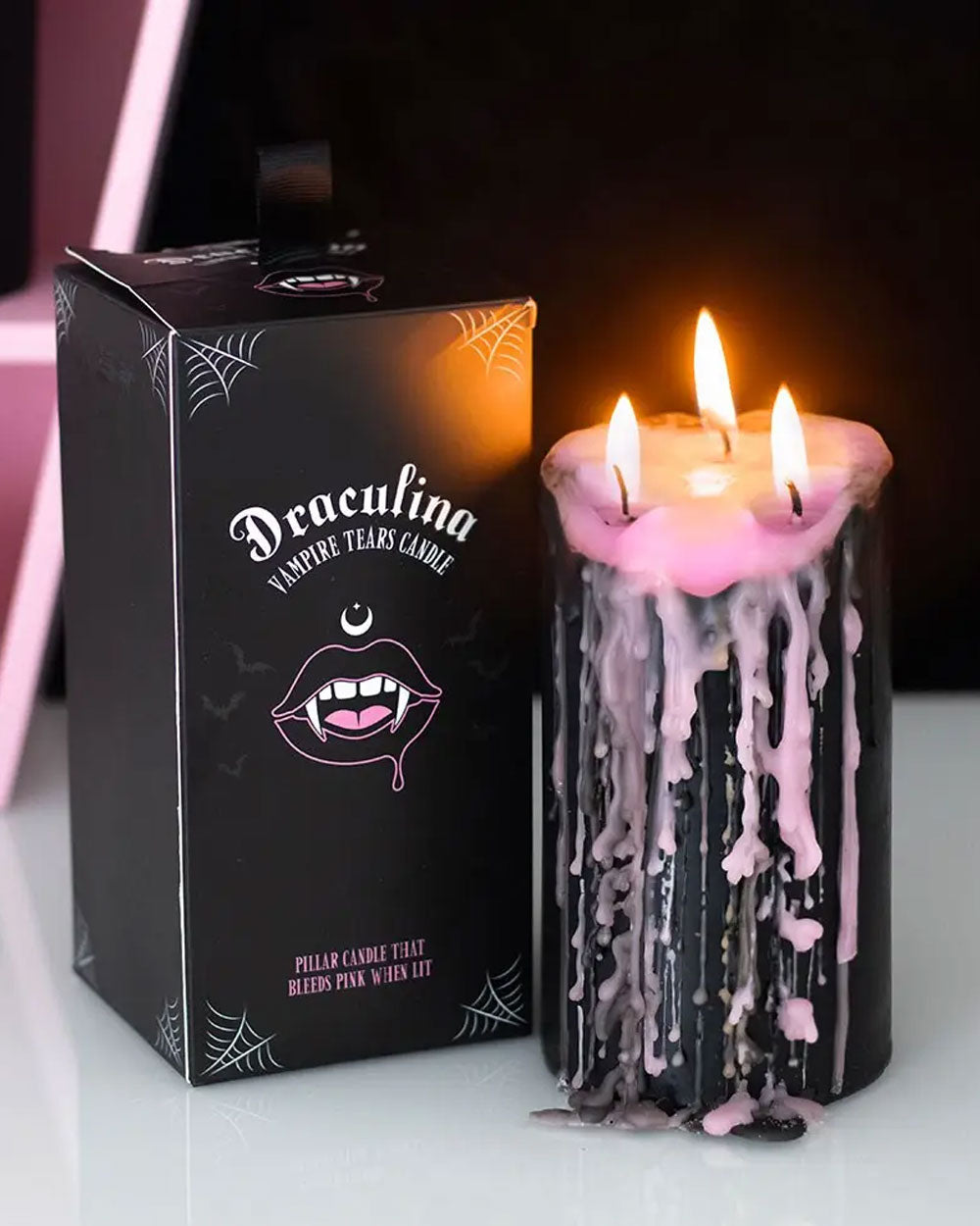 Black pillar candle with pink drip wax, three wicks, in themed box