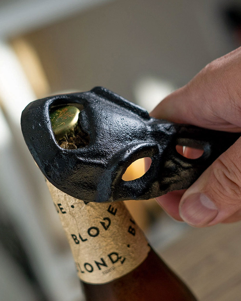 Cast iron raven skull bottle opener lifting a cork from a bottle