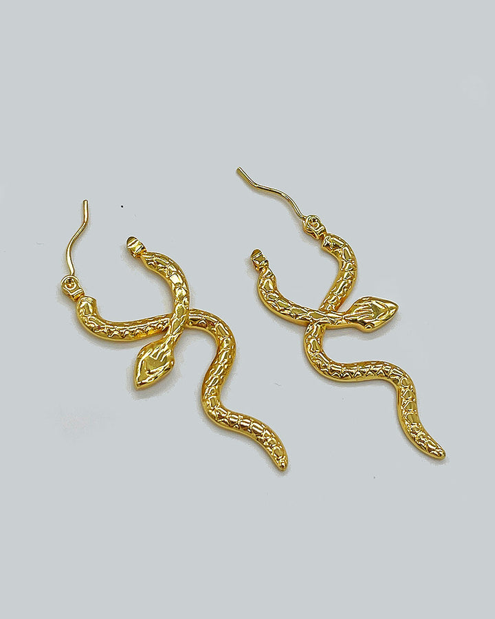Gold serpent coil hoop earrings with long snake tail drop and leaf charm