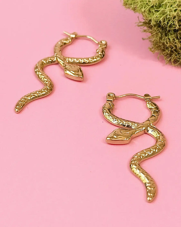 Gold serpent coil hoop earrings with curled snake body and leaf-shaped accents