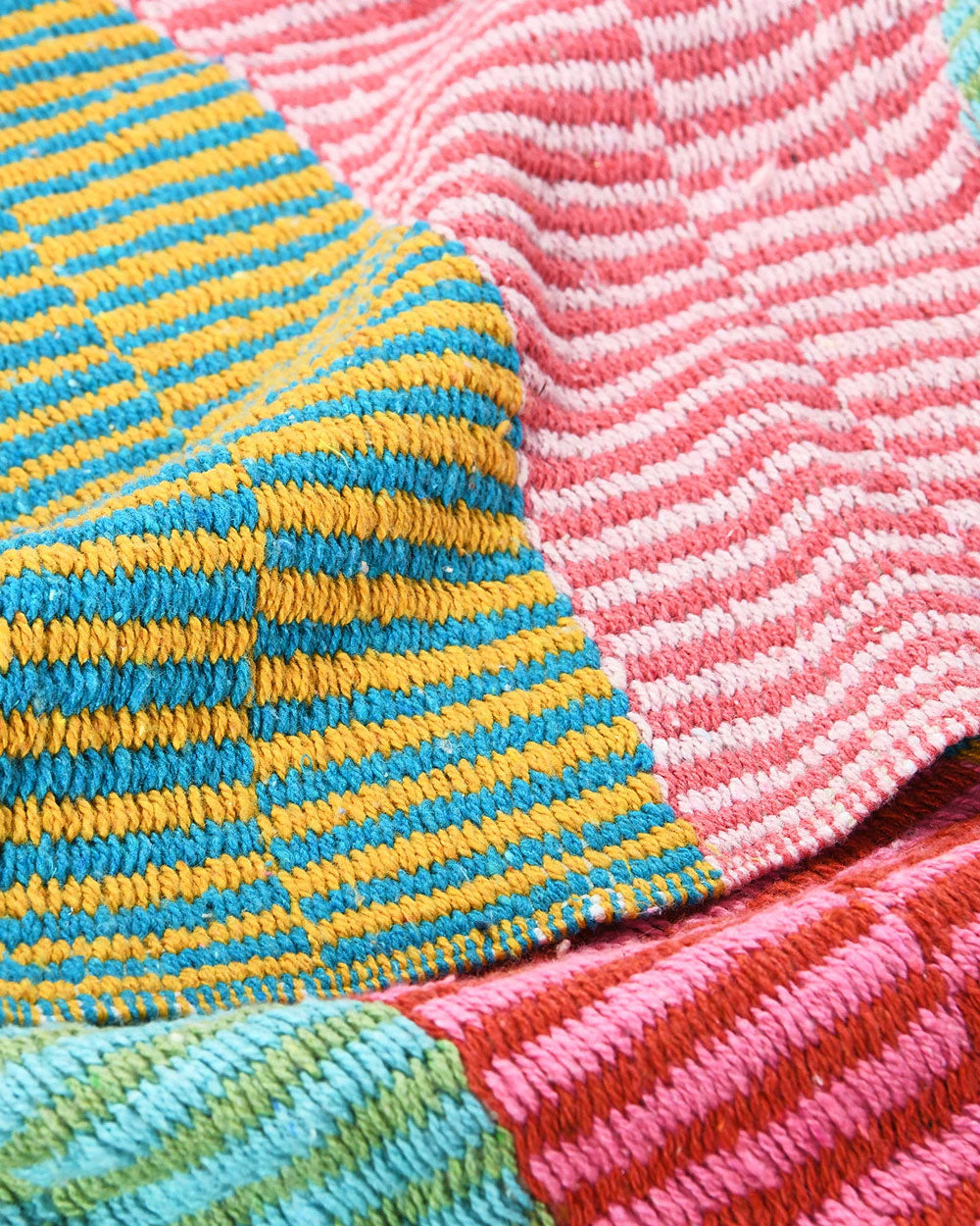 Striped knit throw blanket with pink and yellow-blue sections and fringed edge