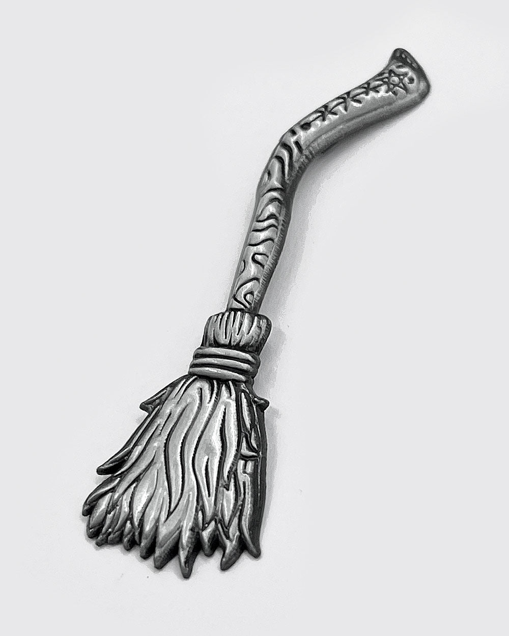 Silver-tone witch broom lapel pin with curved handle and detailed bristle top